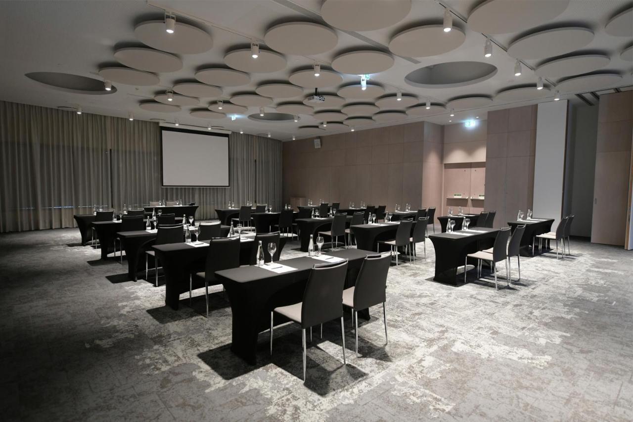 Eurostars Universal Lisboa Dış mekan fotoğraf The image shows a spacious conference or meeting room set up for an event. The room features several rectangular tables arranged in a grid formation, each equipped with black chairs. There are glasses and water bottles on the tables, indicating that 