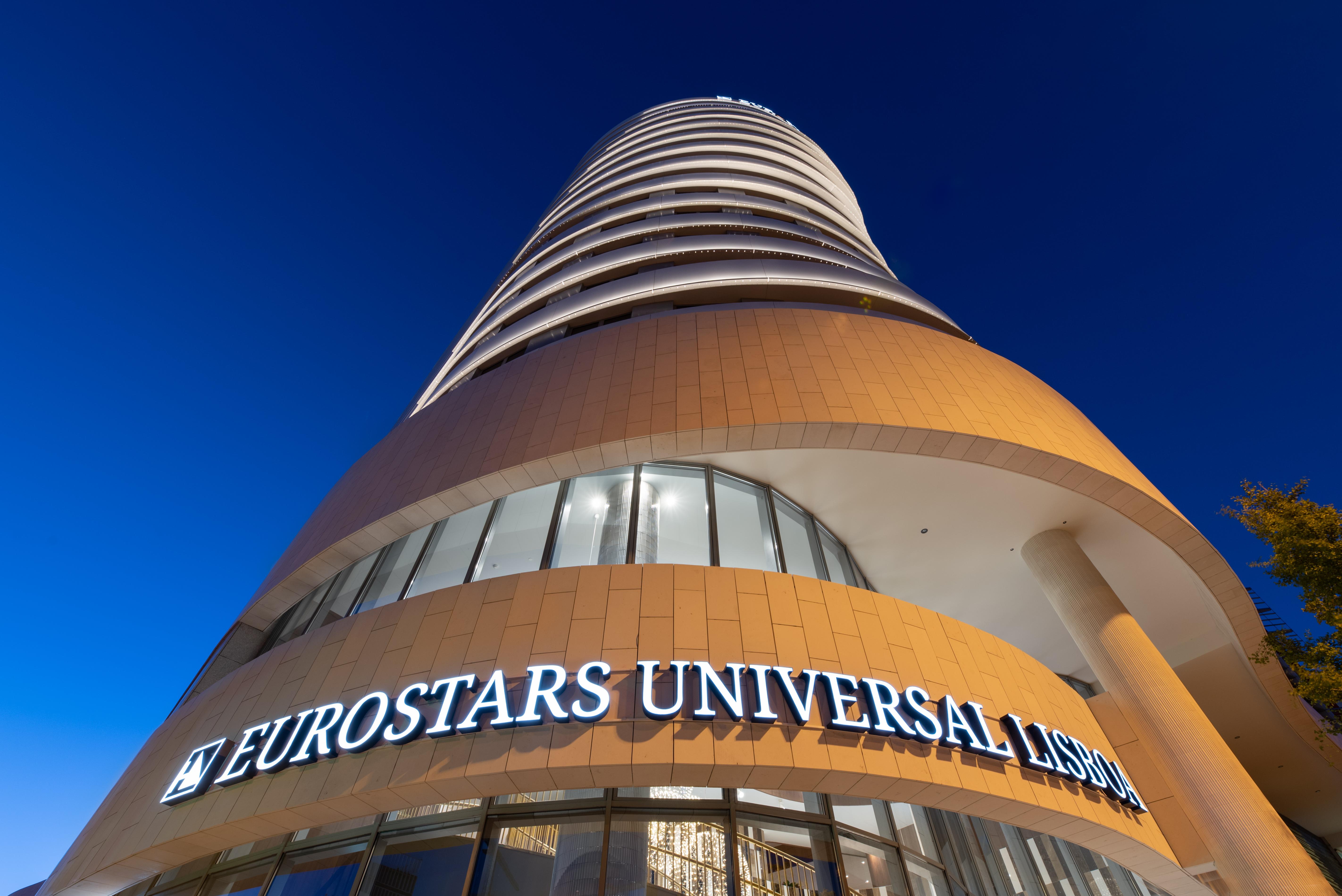 Eurostars Universal Lisboa Dış mekan fotoğraf The photo shows a modern hotel building known as Eurostars Universal Lisbon. The structure is tall and features a curved design, with multiple floors and large windows. The hotel's name is prominently displayed in illuminated letters at the bottom, a