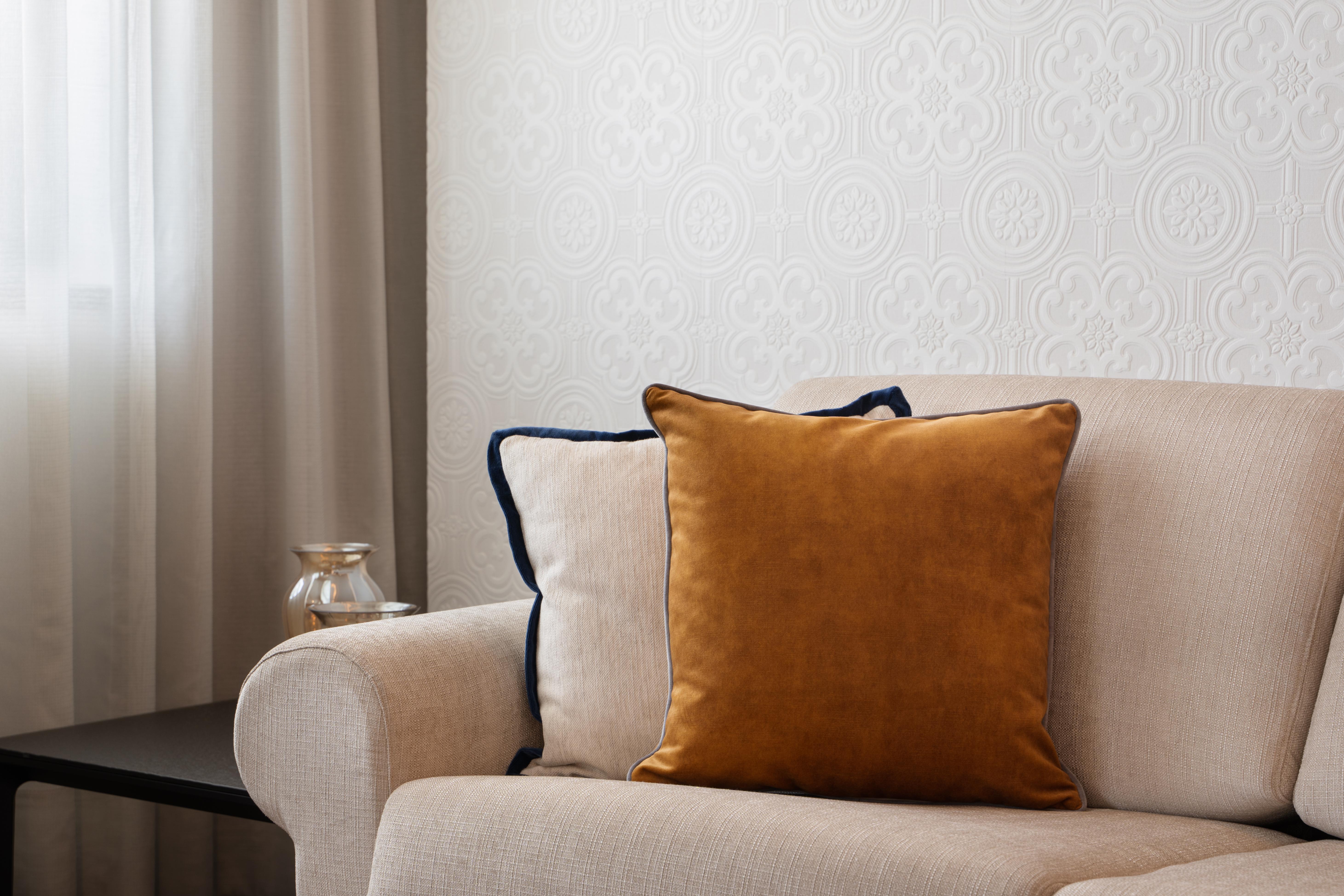 Eurostars Universal Lisboa Dış mekan fotoğraf The photo shows a cozy living room setting featuring a light-colored sofa. On the sofa, there are two cushions: one is a soft beige color with a textured surface, and the other is a vibrant mustard-yellow cushion. The background includes a textured w