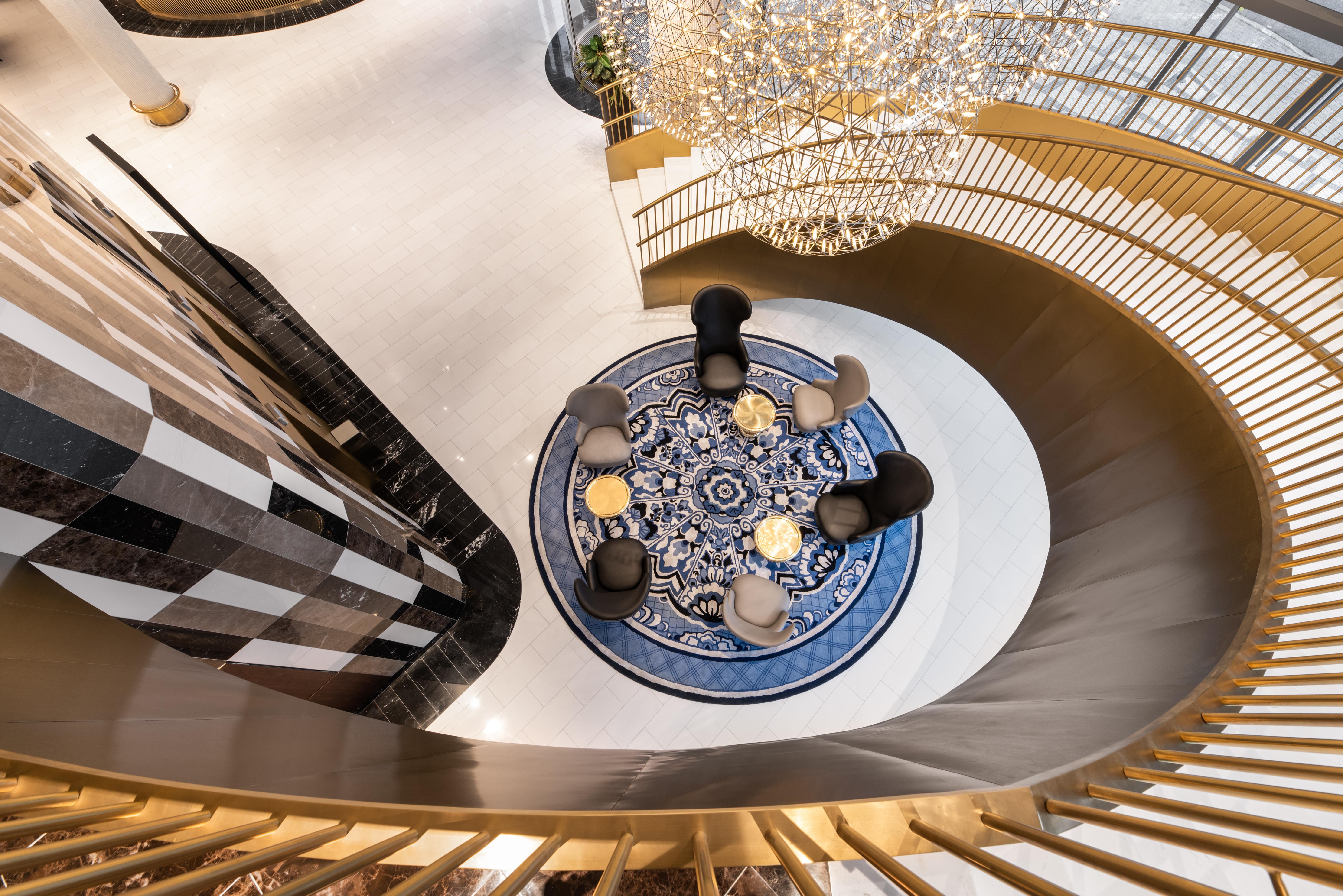 Eurostars Universal Lisboa Dış mekan fotoğraf The photo depicts a stylish indoor space featuring a spiral staircase that leads to a circular area with chairs arranged around a decorative rug. The rug has a blue and white pattern, adding a sophisticated touch to the setting. Above the seating are