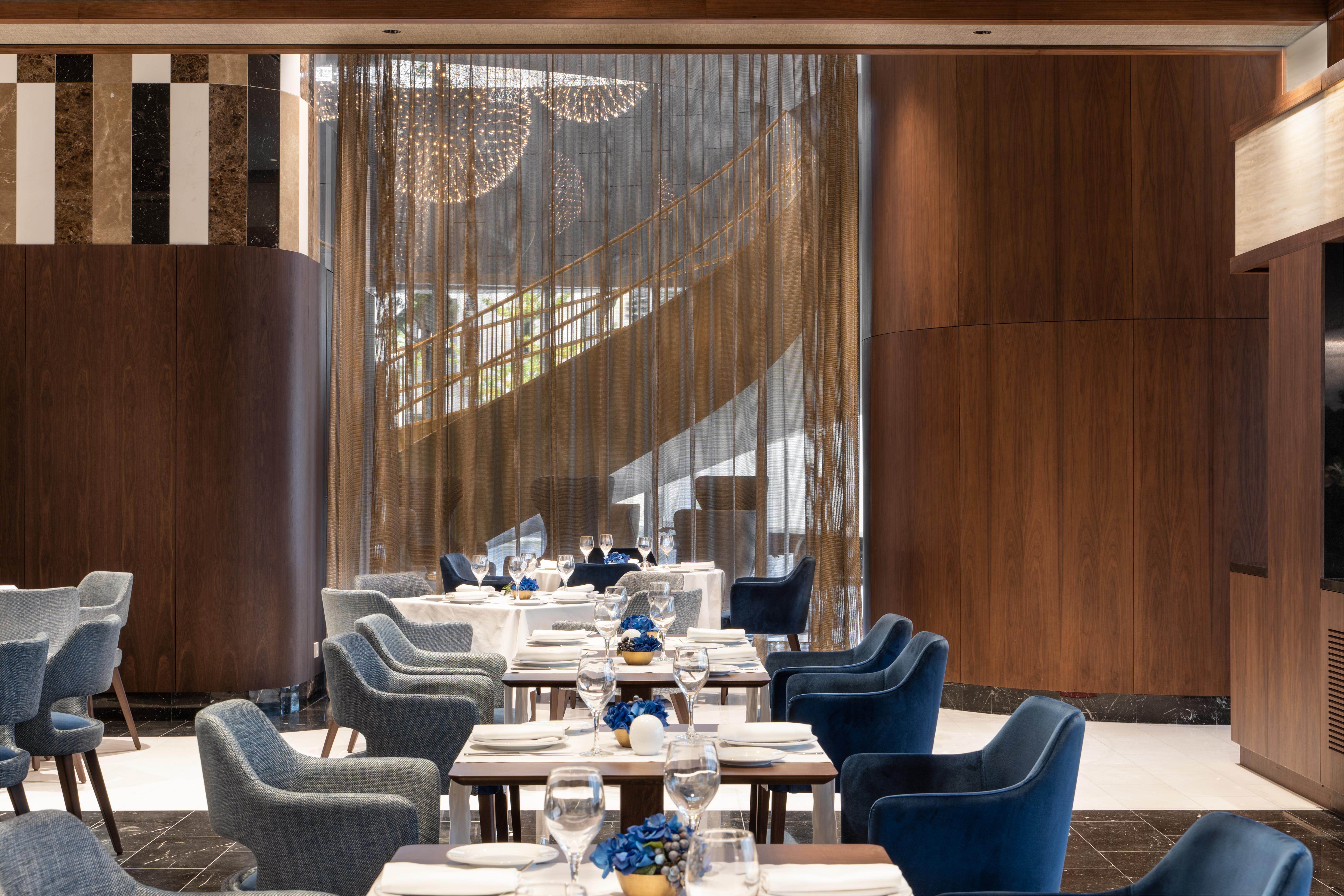 Eurostars Universal Lisboa Dış mekan fotoğraf The photo depicts a stylish dining area in a modern restaurant. The decor features a warm wood paneling contrast with sleek furnishings. There are several tables arranged in the space, each set with white tablecloths and elegant blue decorations. Sof