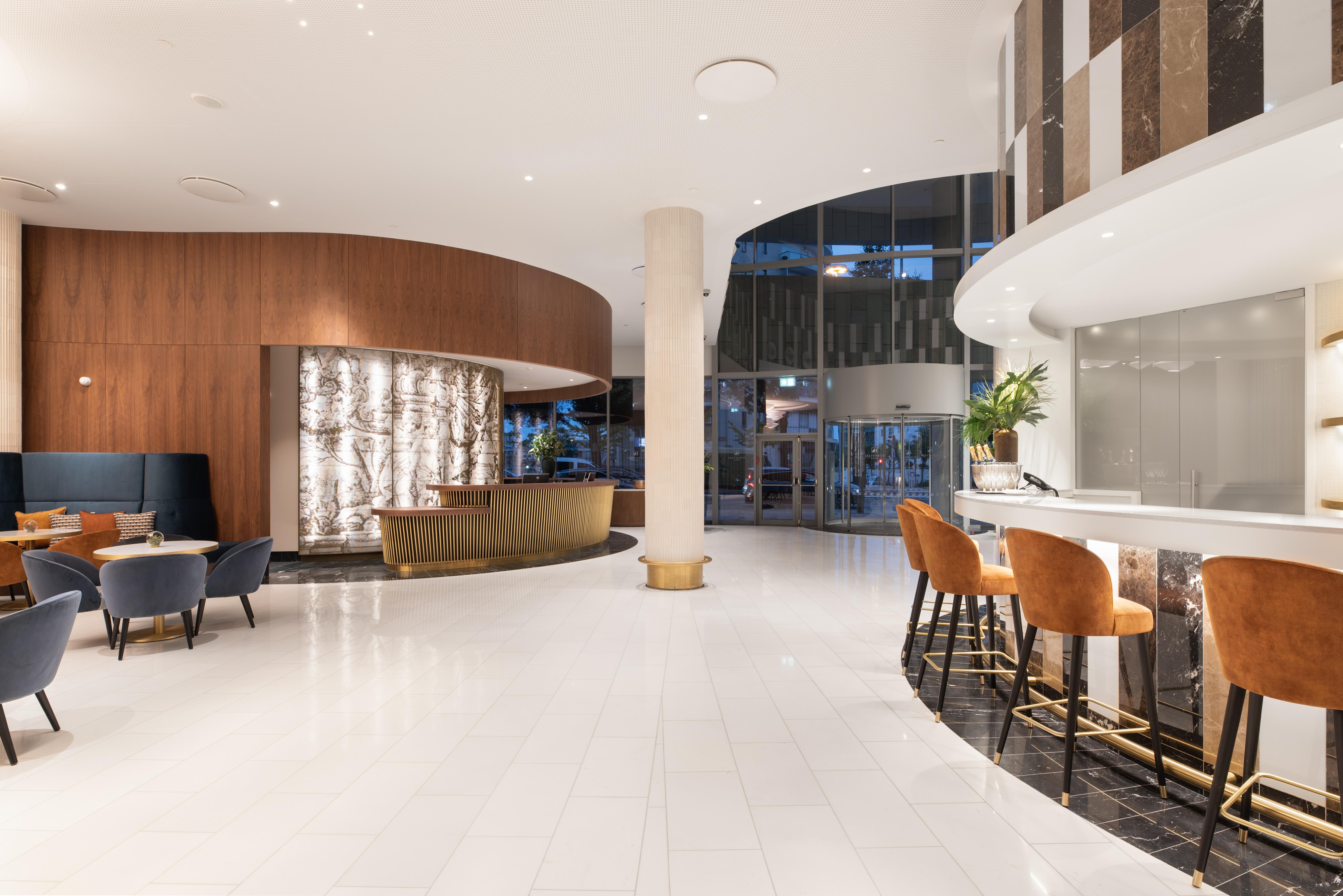 Eurostars Universal Lisboa Dış mekan fotoğraf The photo depicts a modern hotel lobby characterized by a spacious and contemporary design. There is a welcoming reception area with a stylish front desk, featuring an elegant backdrop made of illuminated materials. The flooring is white and glossy, 