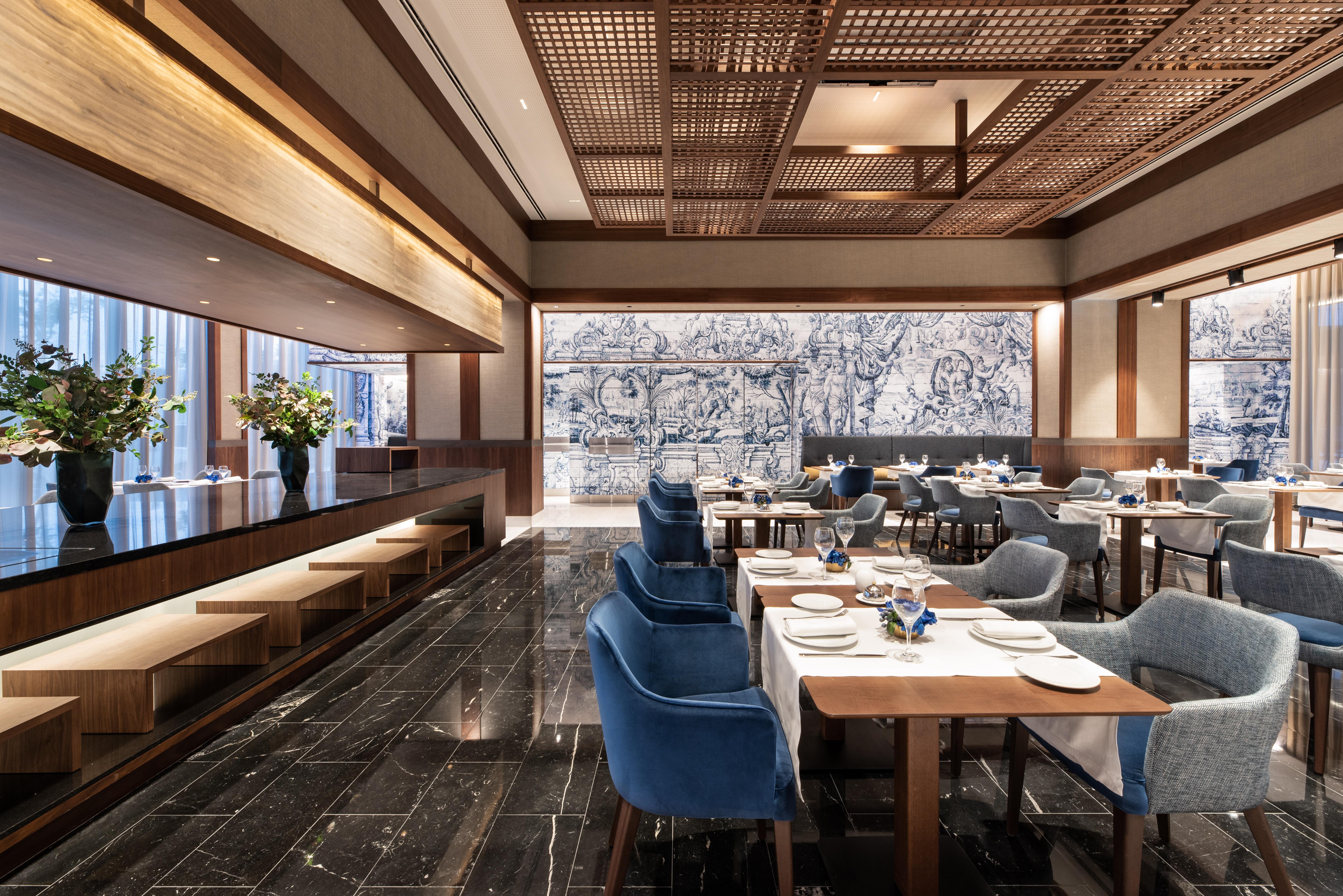 Eurostars Universal Lisboa Dış mekan fotoğraf The photo shows an elegant restaurant interior. It features a modern design with wooden elements and a sophisticated color palette. There are tables set with plates and utensils, and plush chairs in blue and gray colors. The floor is sleek and dark, 