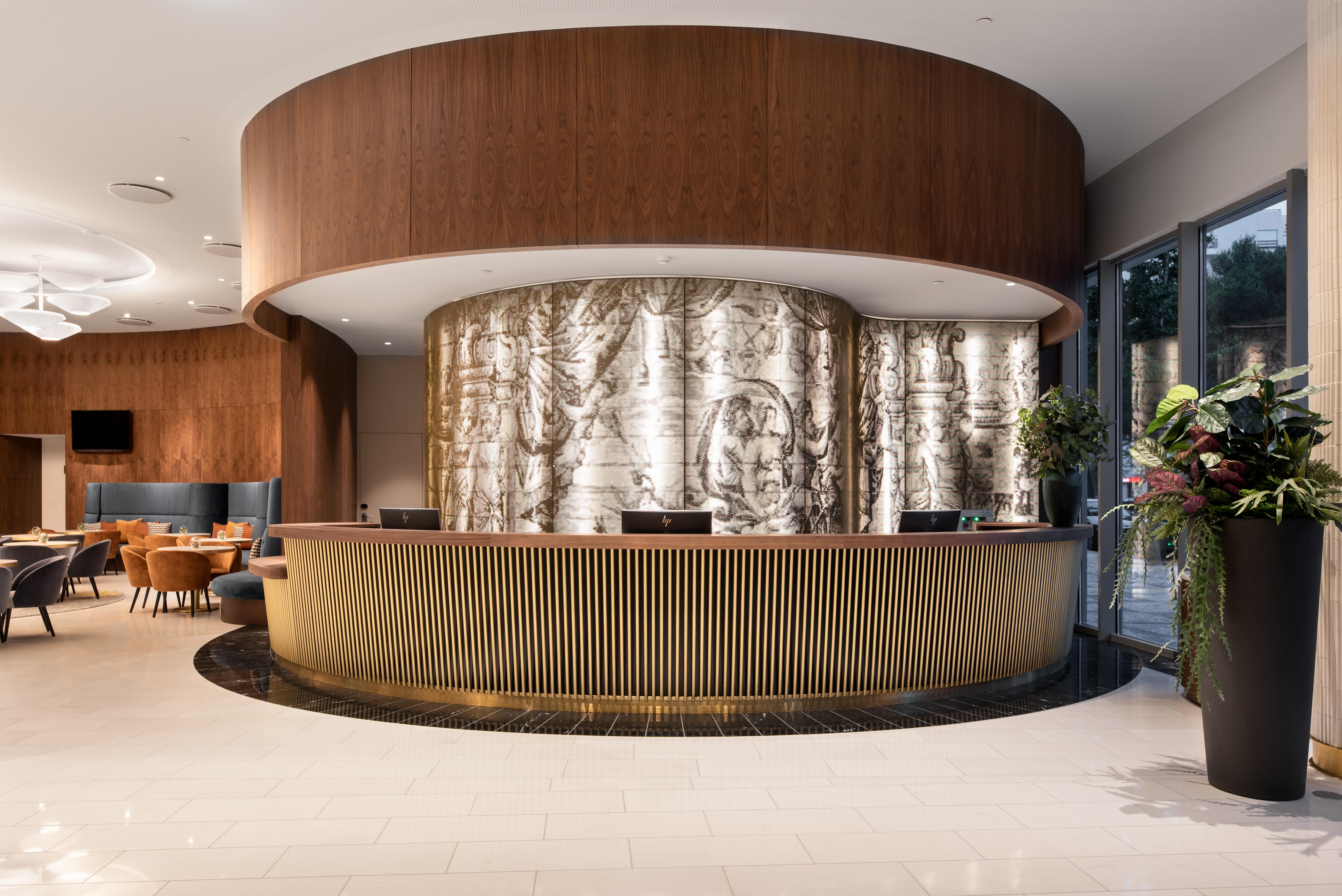 Eurostars Universal Lisboa Dış mekan fotoğraf The photo shows a modern lobby or reception area featuring a stylish front desk. The desk has a curved design with a wooden finish on the top and a ribbed, golden base. Behind the desk, there is a large, decorative wall that appears to have a texture