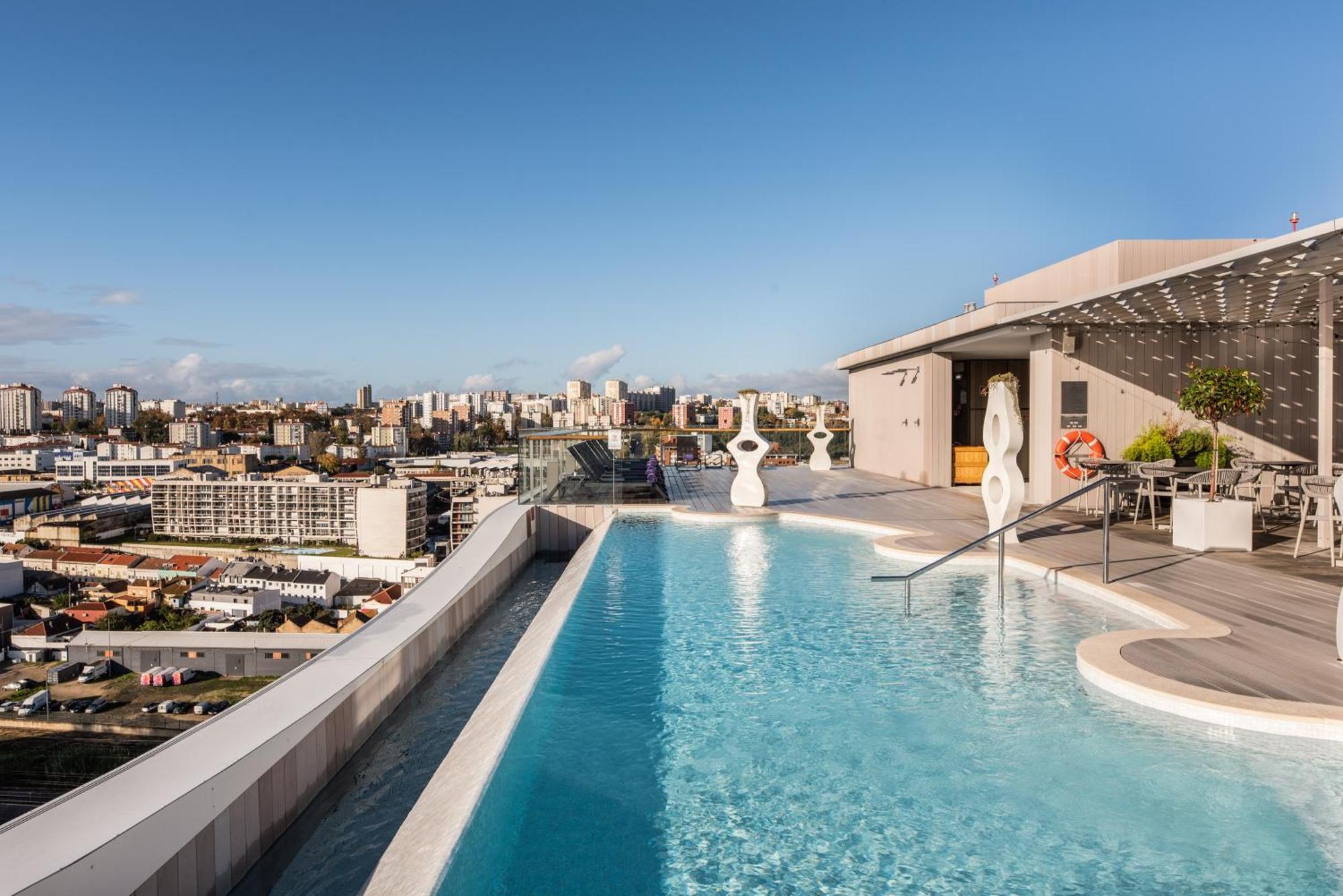 Eurostars Universal Lisboa Dış mekan fotoğraf The photo features a luxurious rooftop infinity pool overlooking a city skyline. The pool has a sleek design, with clean lines and a smooth surface that reflects the sky. Surrounding the pool area, there are modern loungers and stylish decor. In the 