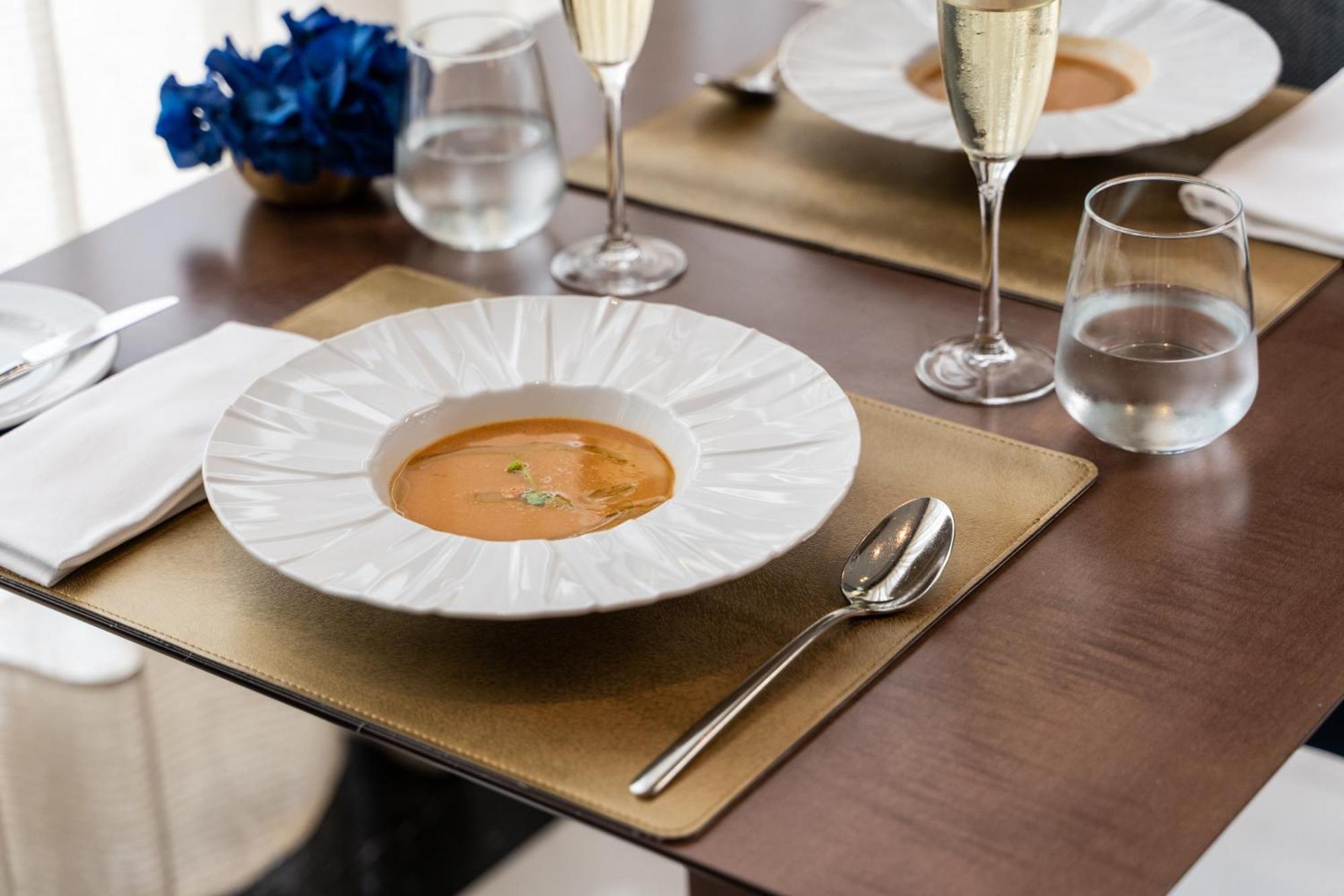 Eurostars Universal Lisboa Dış mekan fotoğraf The photo displays an elegant dining setting. In the center, there's a large white plate with a decorative edge, containing a serving of soup, garnished with a few sprigs of herbs. Surrounding the plate, there are two glasses of sparkling wine, and a